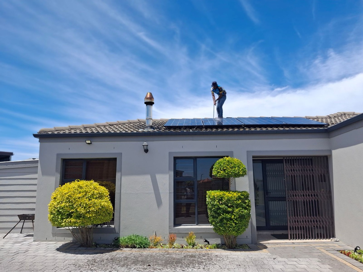 Technician ghar ki chhat par solar panel install karte hue